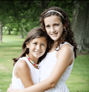 Photo of two young girls, hugging and smiling