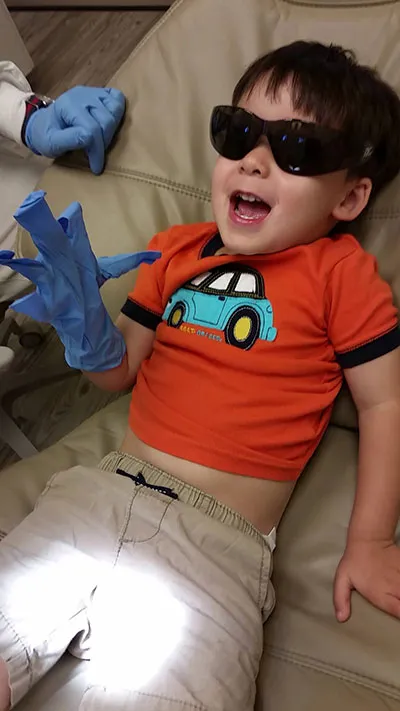 Photo of a young, smiling pediatric dental patient wearing cool shades