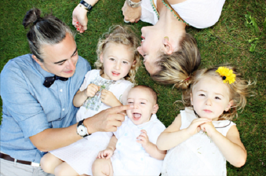 Photo of a laughing family with young children playing on the grass
